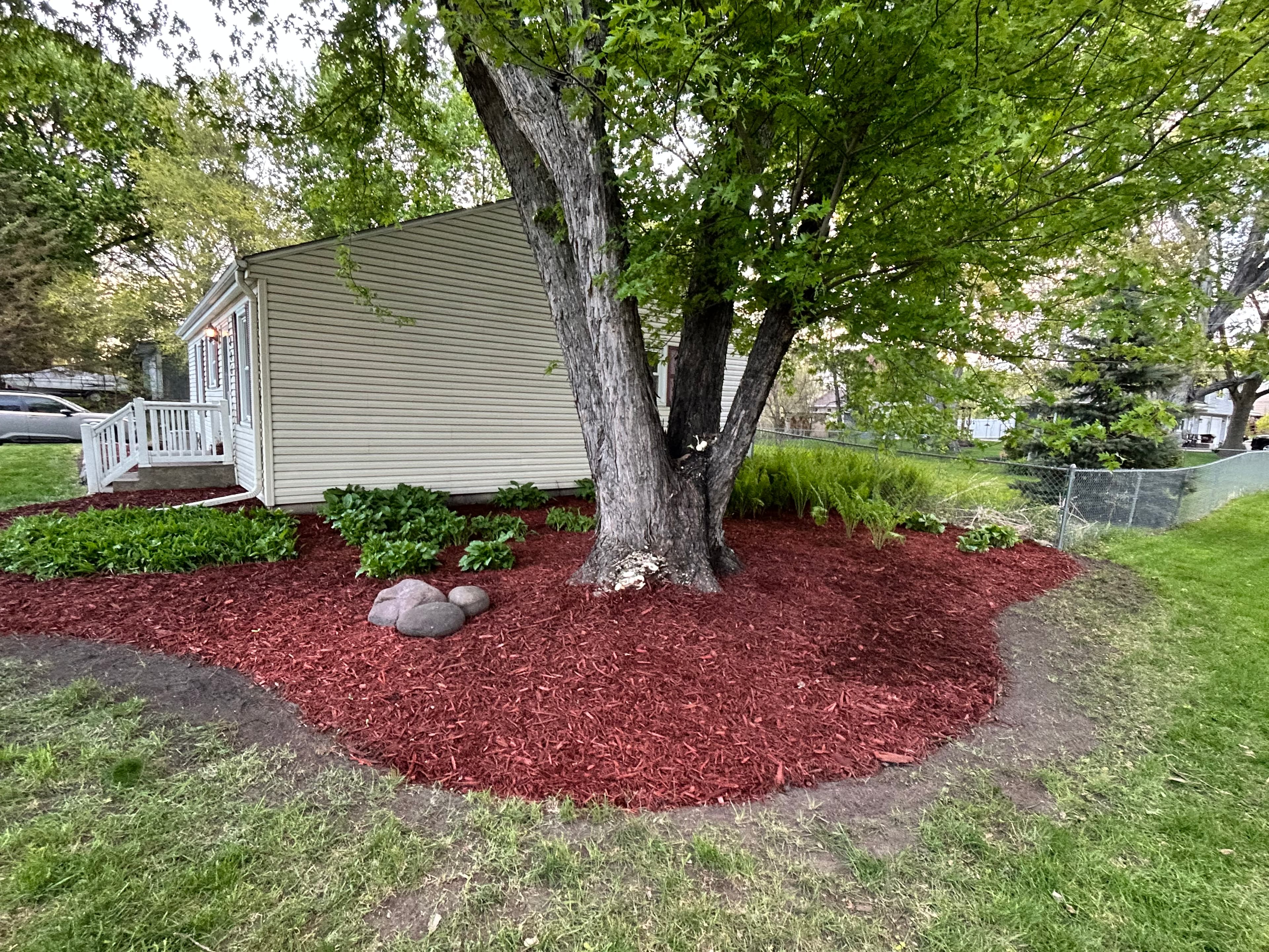 Same landscape bed after fresh mulch and rock installation